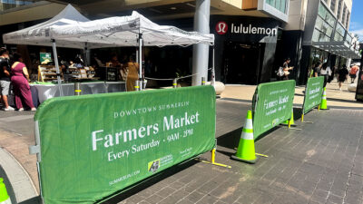 Downtown Summerlin Farmers Market entrance with vendor tents and signs showing the Saturday market hours.