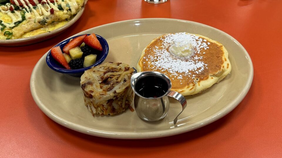 Buttermilk Pancakes, served with fresh fruits, syrup, and hash browns.