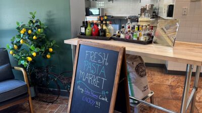 Fresh Pasta Market sign reading “Buy, Take Home, Cook, Enjoy!” at A&M Pasta Lab.