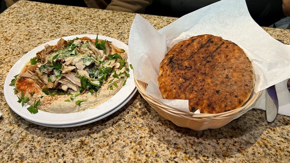 Turkey shawarma served over hummus and tahini with parsley.