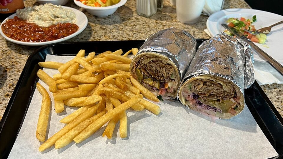 Shawarma laffa wrap cut open to show seasoned meat and fresh vegetables.