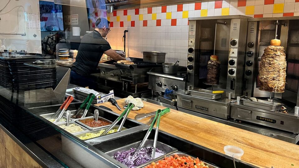 Rotating shawarma spits cooking meat in the open kitchen at Shawarma Vegas.