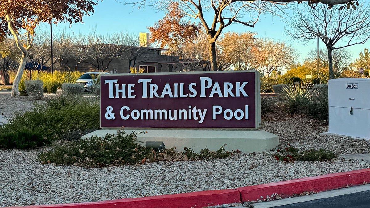 Park entrance sign and pathway at The Trails Park & Pool in Summerlin, Las Vegas, with landscaping and trees visible.