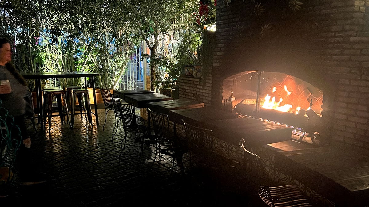 Outdoor fireplace at Park on Fremont in downtown Las Vegas surrounded by greenery, string lights, and eclectic patio decor.