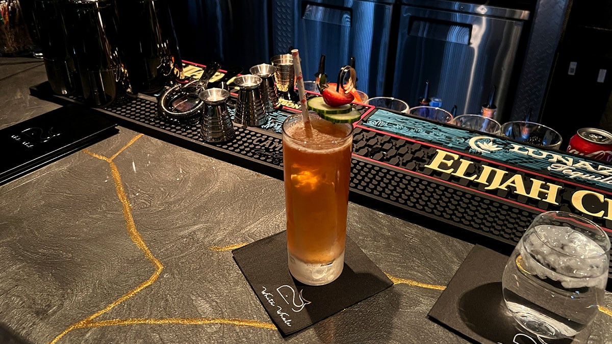 The Troublemaker cocktail served tall and clear with a light blush, featuring strawberry, cucumber, mint, and ginger.