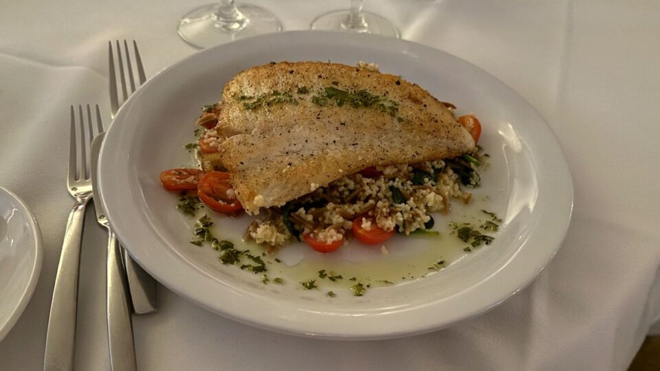Pan-seared halibut served with couscous, orzo, sweet tomatoes, baby spinach, and lemon gremolata at Vintner Grill.