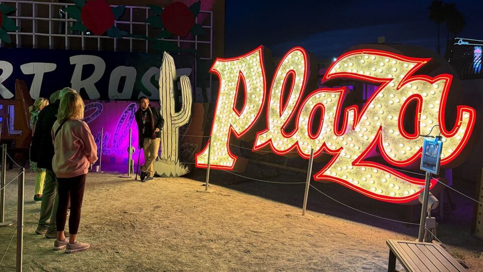 Tour guide sharing the history of the Plaza Hotel neon sign with visitors at The Neon Museum