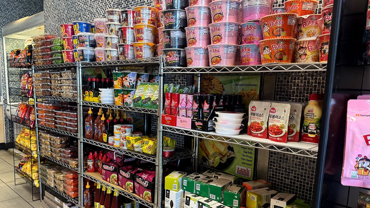 Assorted Asian food products such as noodles, sauces, snacks, and packaged ingredients arranged on grocery store shelves.