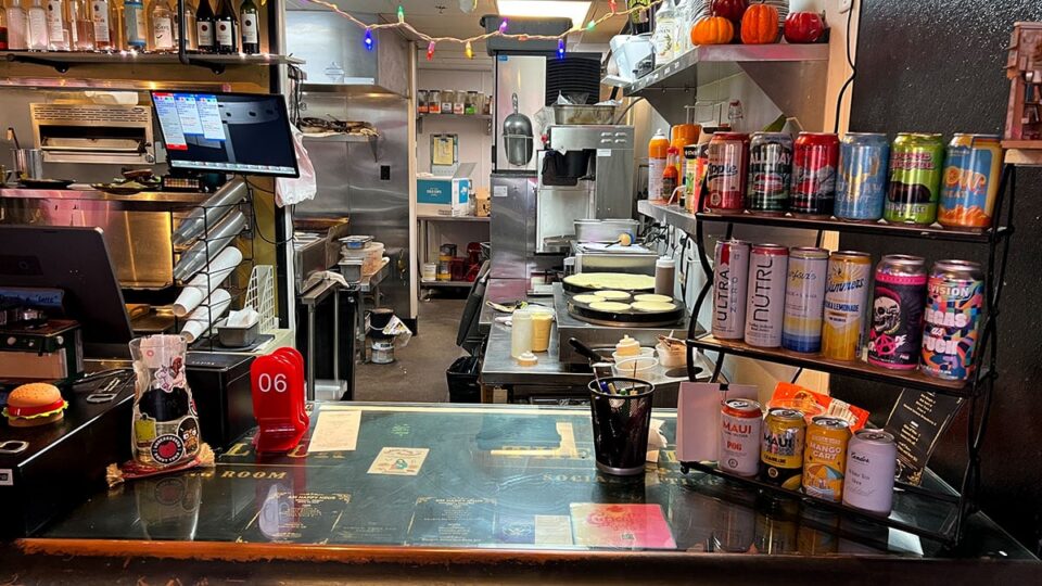 Open kitchen counter at The Parlour Downtown with beer cans and pancakes cooking on a griddle.