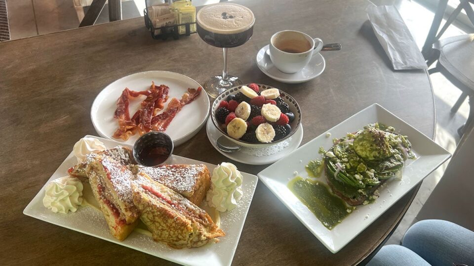 Full brunch spread at Le Café Central in Chinatown Las Vegas featuring PB&J French toast, pesto salmon, fruit, bacon, and coffee.