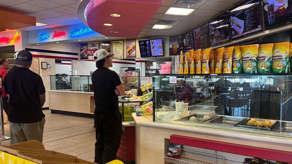 Menu board at Lee’s Sandwiches showing available sandwiches, drinks, and other offerings.