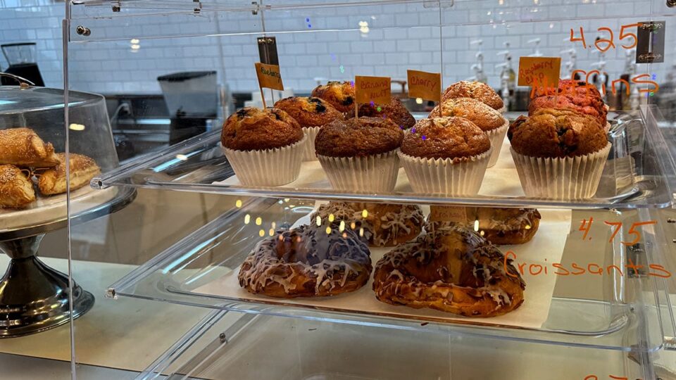 Fresh muffins and croissants displayed in a pastry case at Exit Zero Coffee
