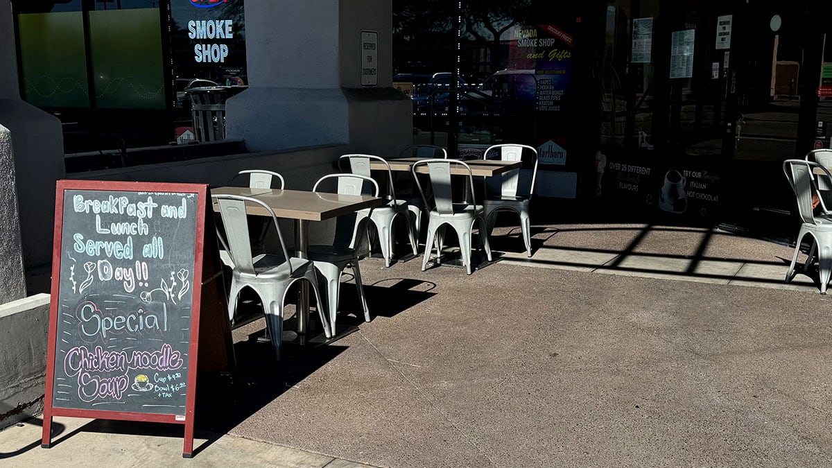 Outdoor patio seating area at Solo Qui café on Lake Mead with tables and chairs in front of the storefront.