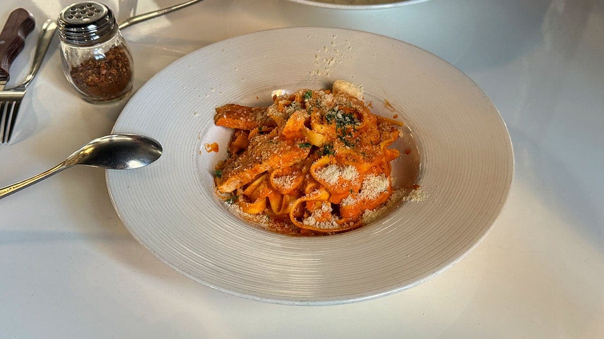 A plate of Rigatoni Piccante with spicy grilled chicken, cherry tomatoes, red onion, and creamy sauce at Brunello Italian restaurant in Sun City Summerlin.