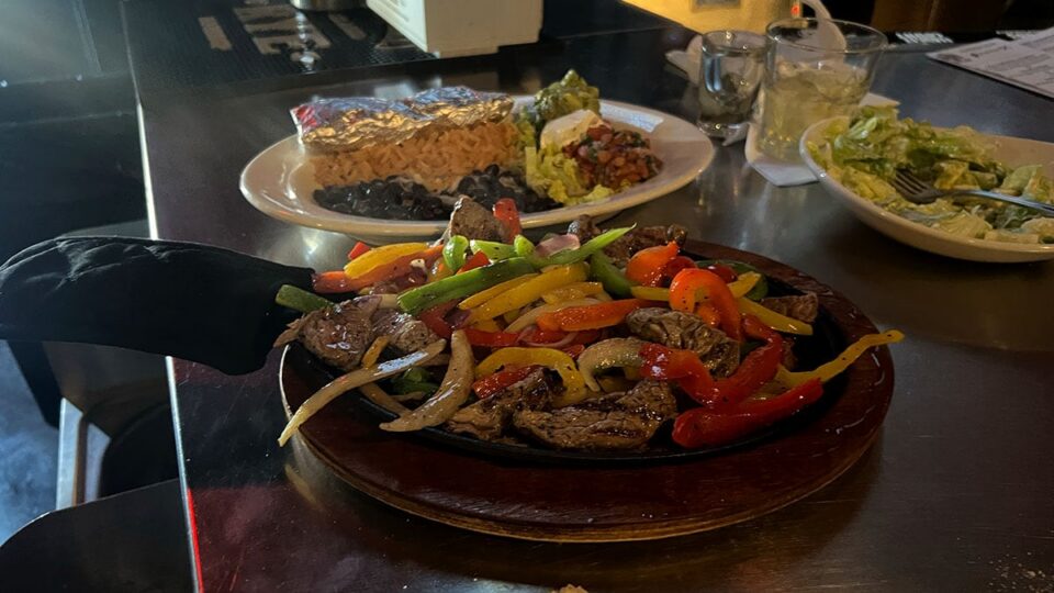 Sizzling steak fajitas with peppers and onions on a hot skillet