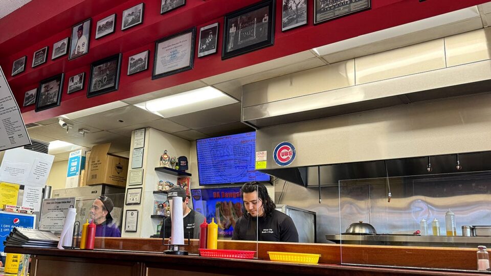 Staff preparing Chicago style hot dogs behind the counter at Windy City Beefs-N-Dogs.