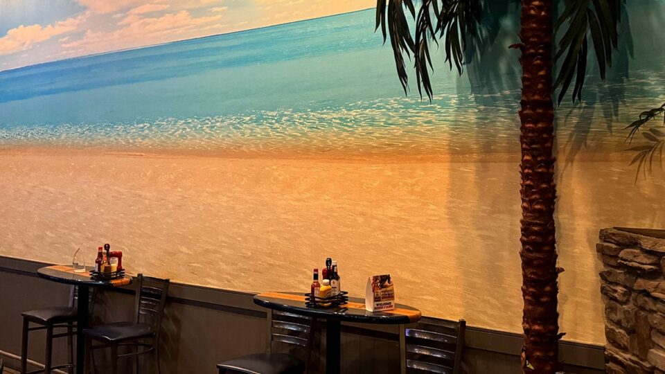 Surfboard shaped bar tables inside Sagos Tavern with tiki themed decor.