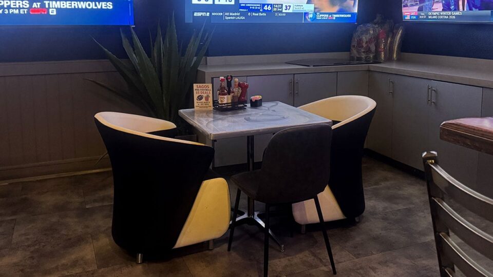 Dining table area at Sagos Tavern with bar stools and seating options in the background.