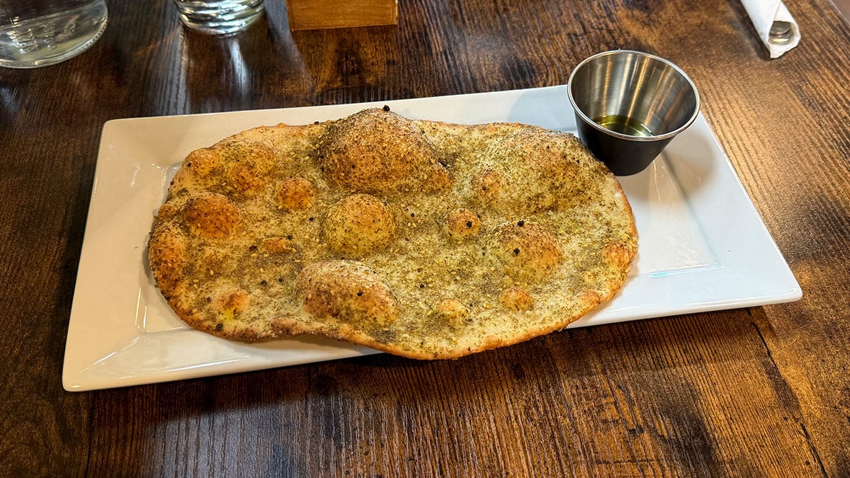 Freshly baked house-made za’atar flatbread served warm with fragrant herbs and olive oil.