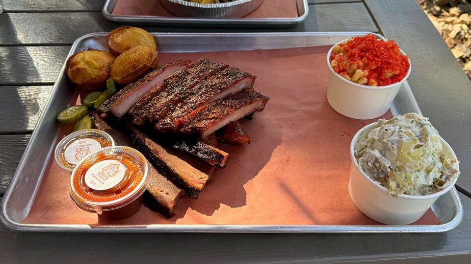 Three meat BBQ combo with brisket ribs sausage and sides at Wild Fig BBQ.