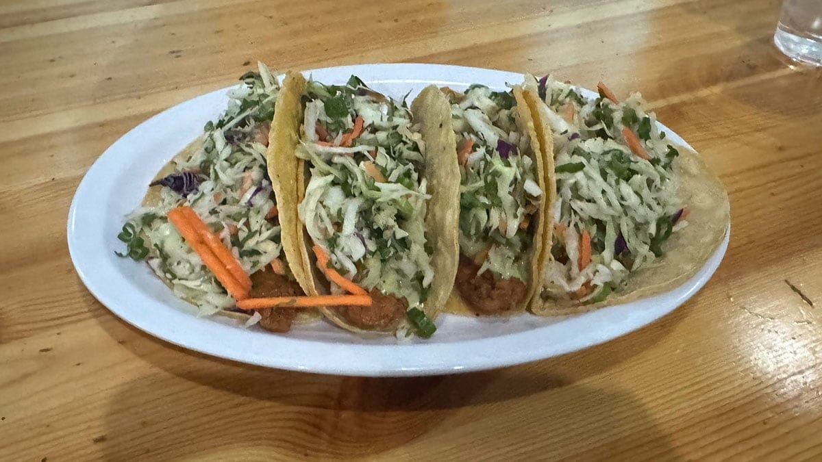 Plate of fresh fish tacos at Wahoo’s Fish Taco in Boca Park, served without cheese and topped with cabbage and sauce.