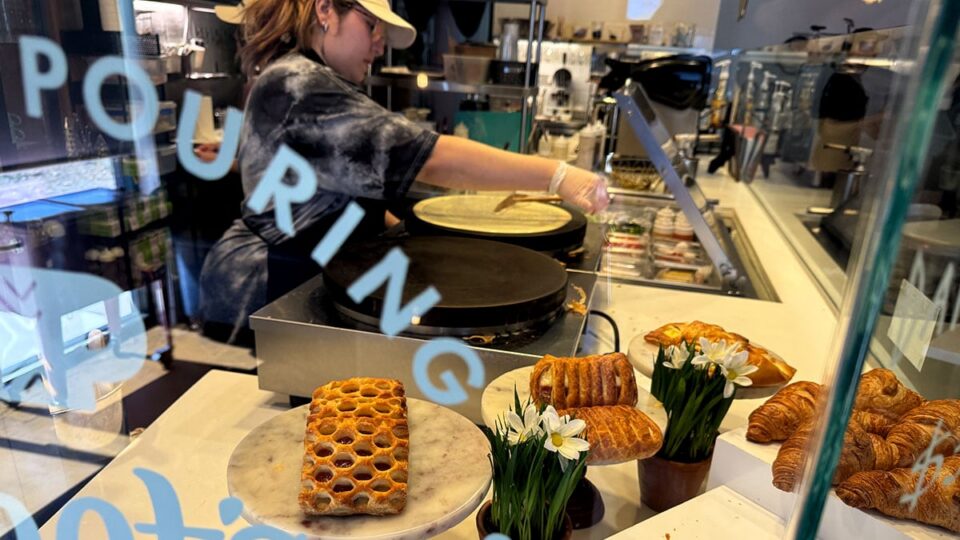 Fresh pastries displayed at Cafe Mong with staff preparing crepes behind the counter.