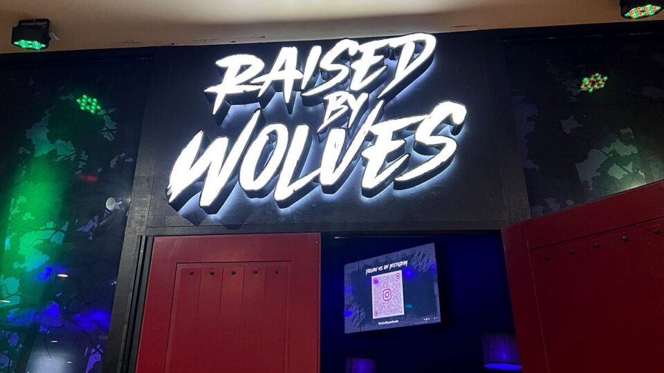 Raised By Wolves bar entrance sign near the red door on the second floor of Neonopolis.