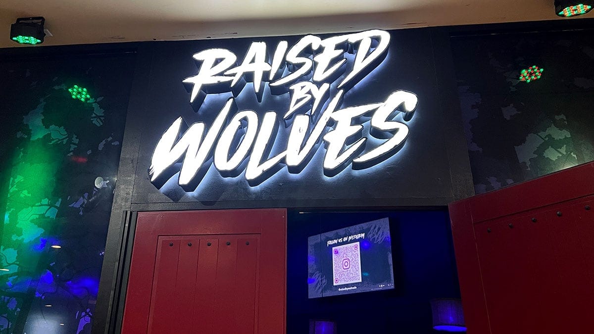 Raised By Wolves bar entrance sign near the red door on the second floor of Neonopolis.