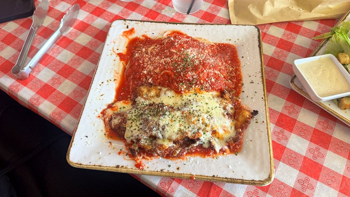 Plate of pasta topped with crispy chicken Parmesan and marinara sauce at Santina’s New York Pizzeria.