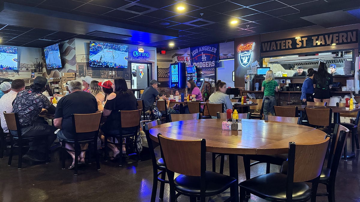 Group of people at Johnny Mac’s watching a basketball game on TV, enjoying drinks and a lively bar atmosphere.