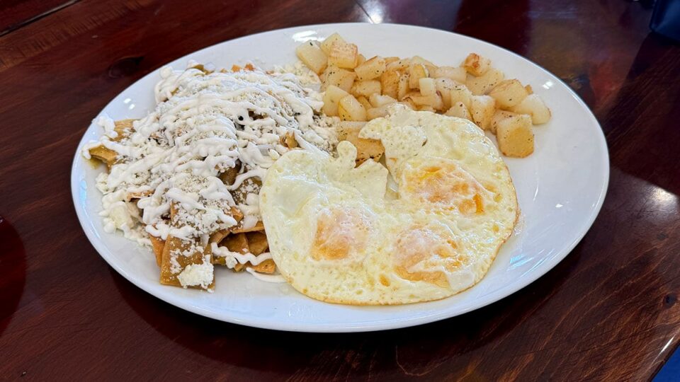 Plate of chilaquiles verdes topped with eggs, crema, and cotija cheese at El Zarape on Pecos.