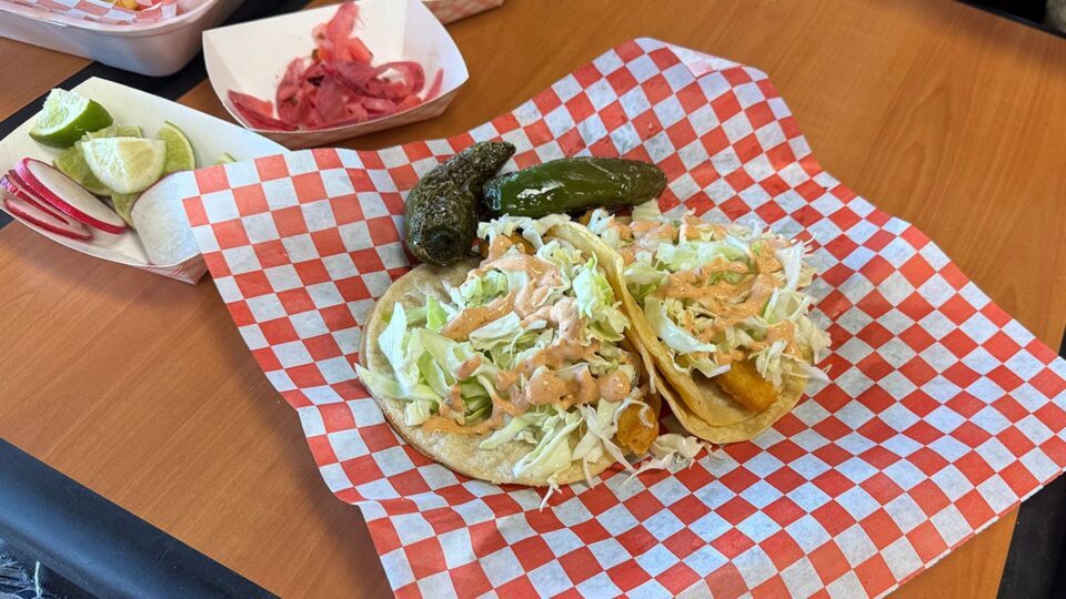 Crispy fish tacos on flour tortillas topped with cabbage and sauce at Tacos Los Barrios.