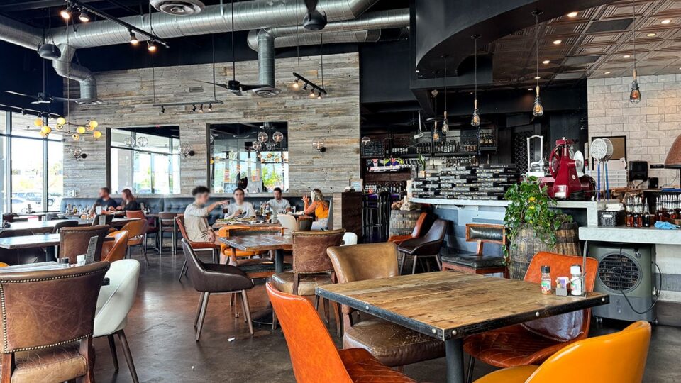Interior dining area of Settebello Pizzeria with wood tables and industrial design