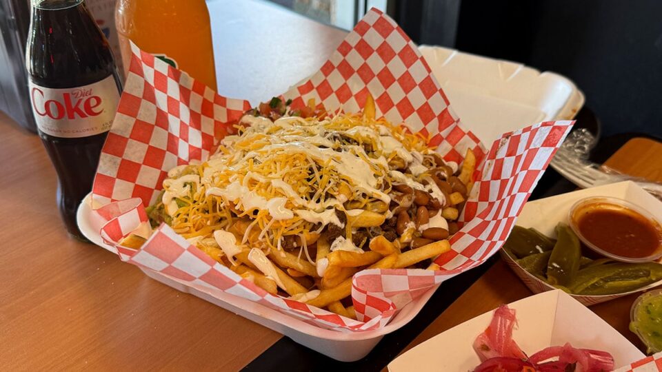 Loaded carne asada fries with beans, sour cream, guacamole, cheese, and pico de gallo at Tacos Los Barrios.