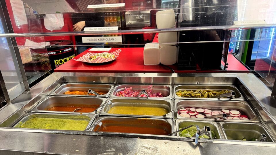 Taco toppings including jalapenos, salsa, onions, and lime at Tacos Los Barrios.