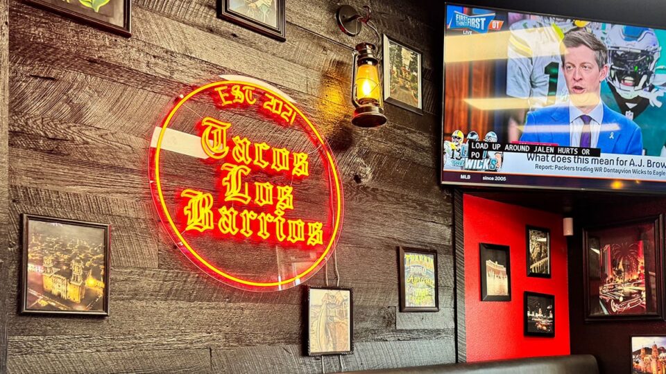 Neon Tacos Los Barrios sign inside the restaurant with EST 2021 displayed on the wall.
