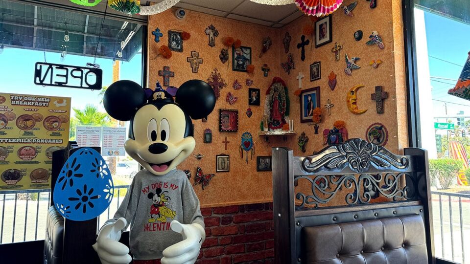Life-size Mickey Mouse figure displayed in front of a wall filled with decorative crosses at El Zarape.