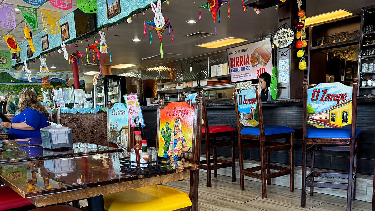 Hand-carved wooden chairs painted with the El Zarape name and colorful designs inside the restaurant.
