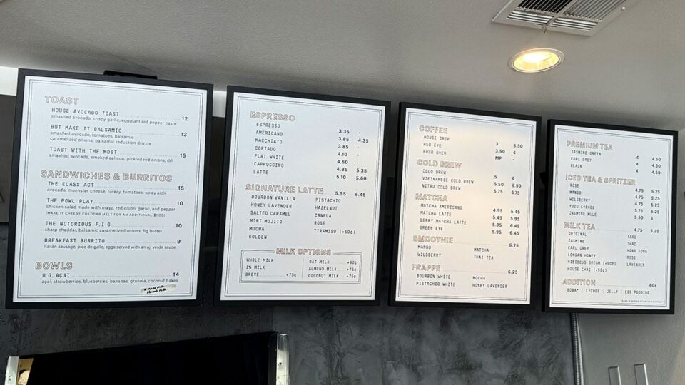 Menu board at Aware Coffee showing coffee drinks, pastries, and breakfast options.