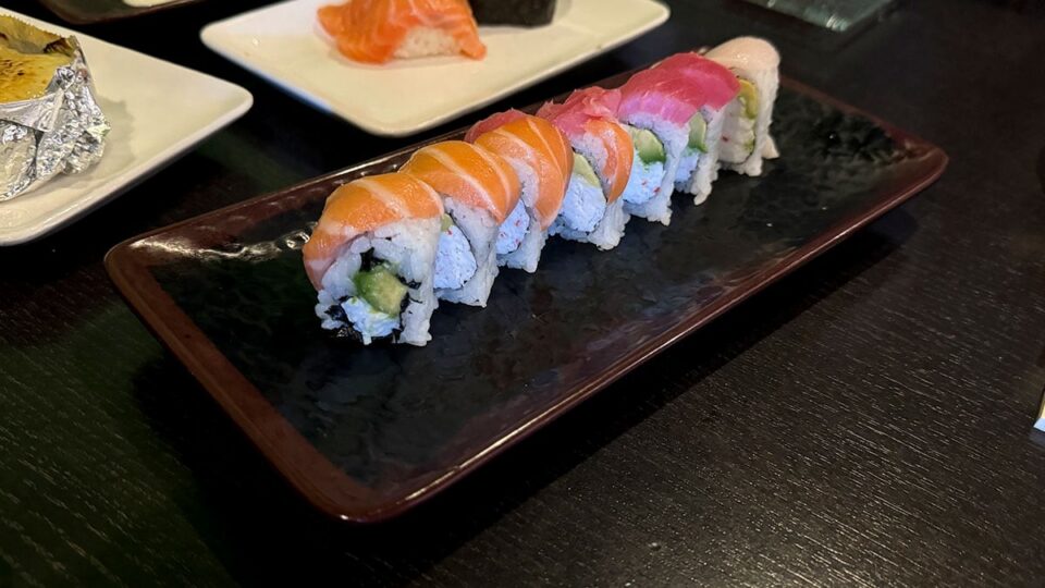 A colorful rainbow roll topped with fresh slices of salmon, tuna, and other fish at Sasa Sushi.