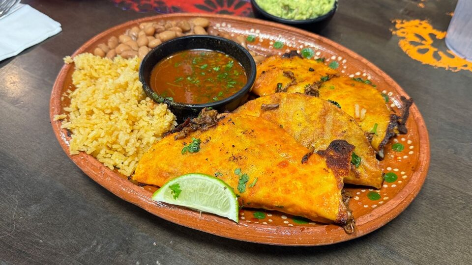 Close up of quesabirria tacos with birria, cheese and dipping consome at Carolina's Mexican Kitchen