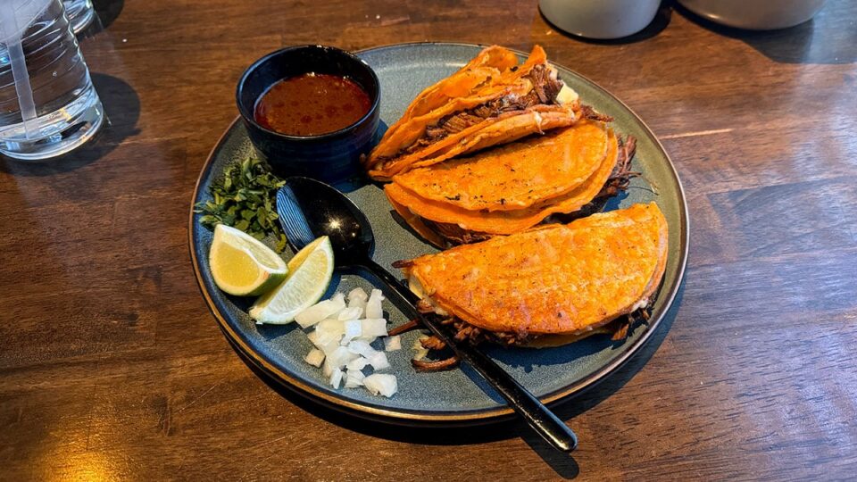 Quesabirria tacos served with onion, cilantro, lime, and consommé at Ta’Chingón.