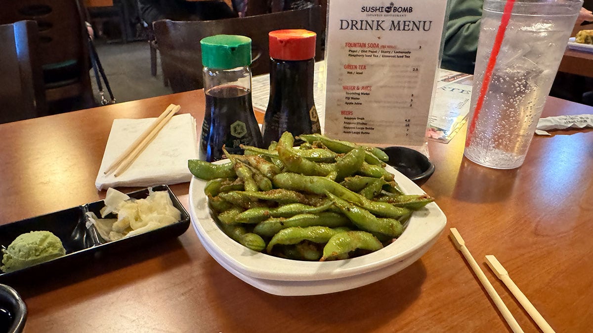 a bowl of spicy garlic edamame coated in flavorful sauce at sushi bomb