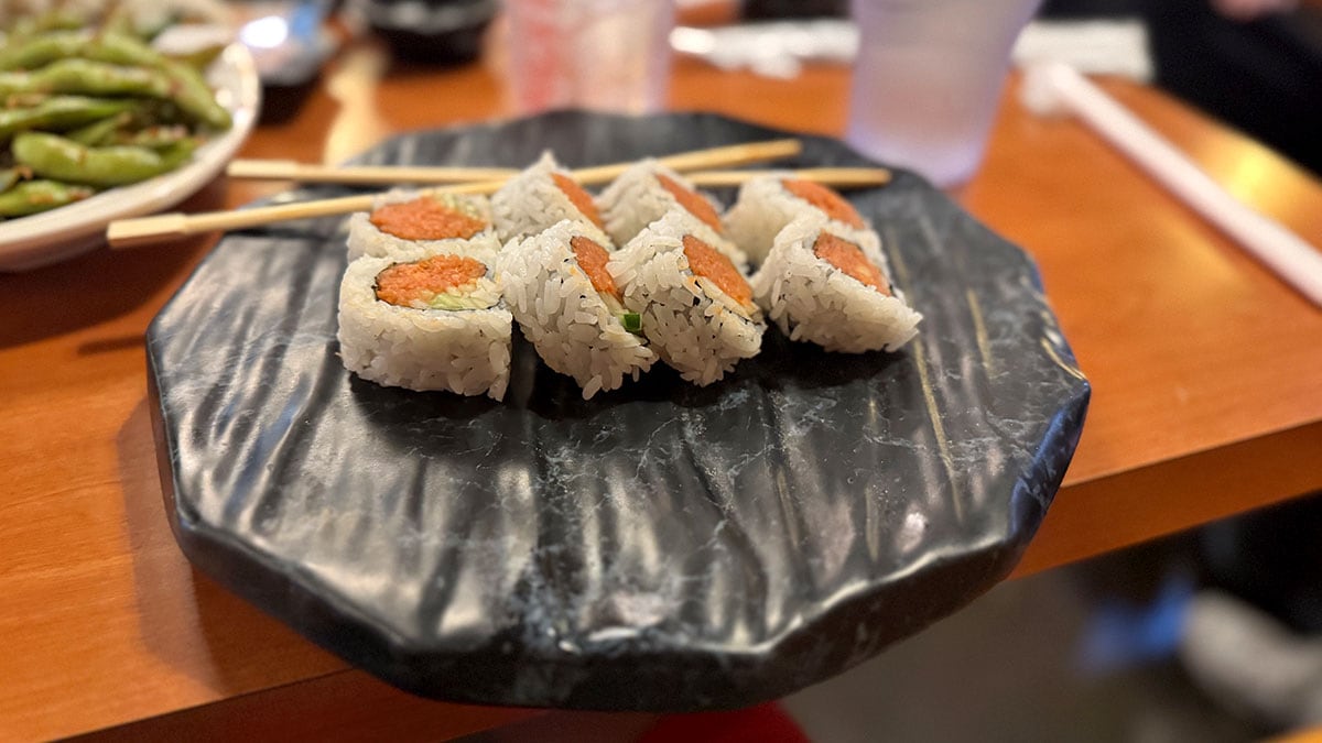 fresh spicy tuna roll topped with sauce and sesame seeds at sushi bomb