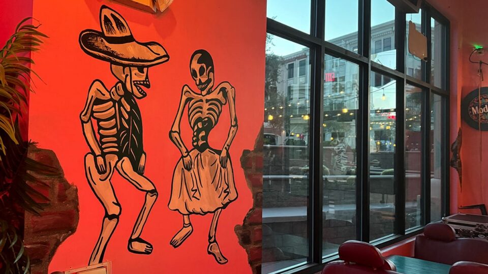 Colorful mural of two dancing skeletons on the wall inside Pinches Tacos.