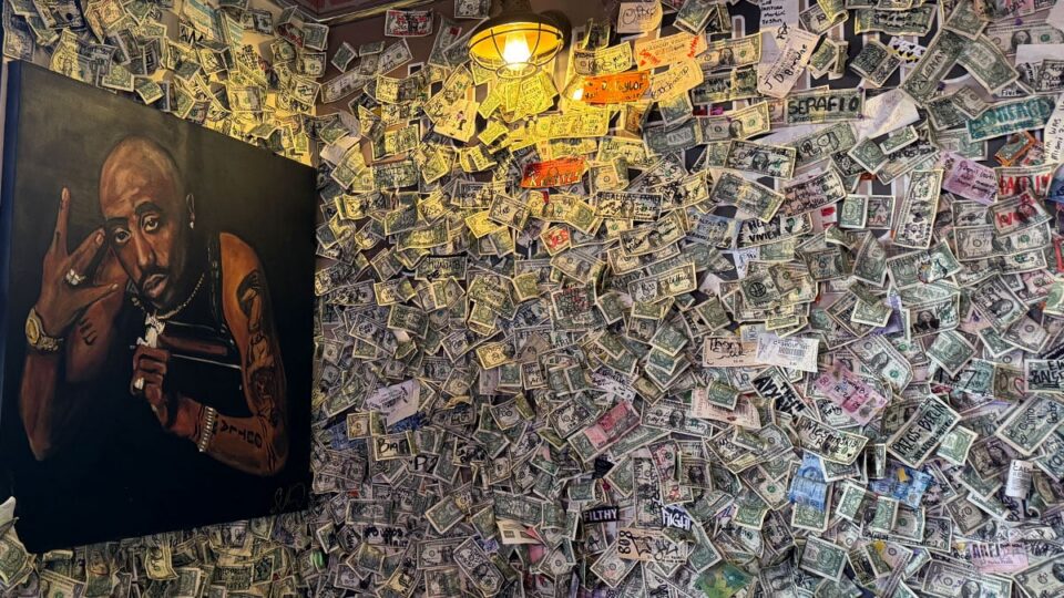 Tupac Shakur wall art backed by signed dollar bills from guests at Dirt Dog Southwest.