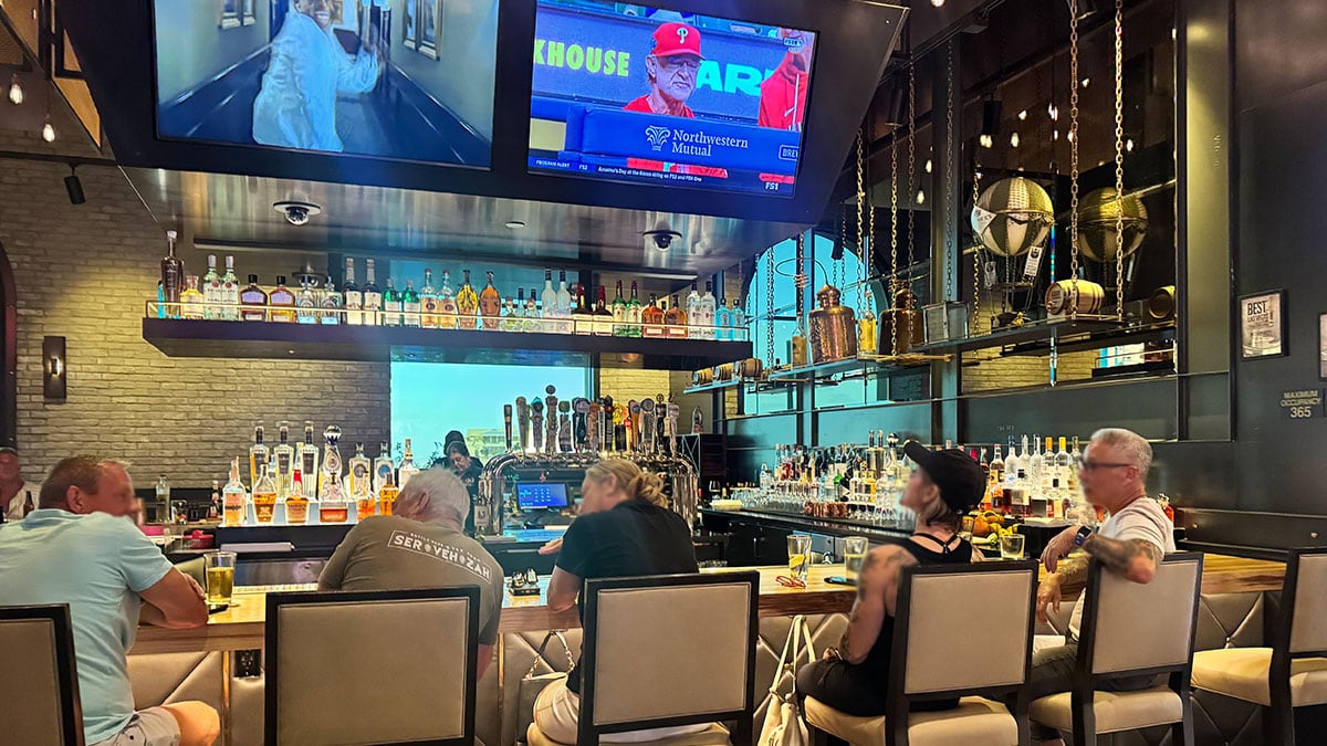bar seating area with large televisions showing sports at 90 NINETY Bar + Grill