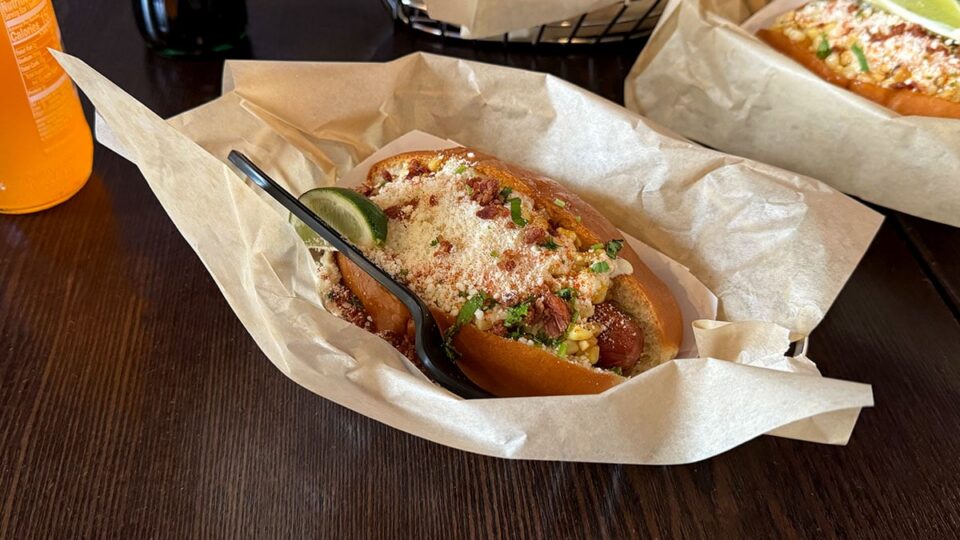 Elote hot dog topped with corn, cotija, lime mayo, chili powder, and cilantro at Dirt Dog Southwest.