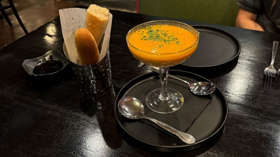 Bowl of lobster bisque alongside house bread and olive oil at Tres Social Tapas.