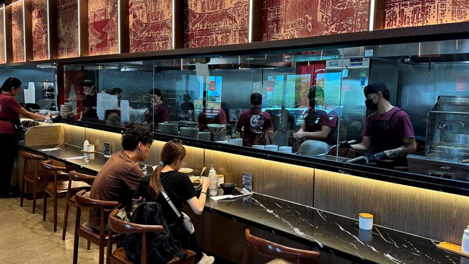Open kitchen view at Shang Artisan Noodles showing chefs preparing noodles.